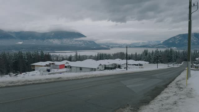 Panning Shot of a Residential Neighbourhood in Winter With Lake and Mountains in the Background