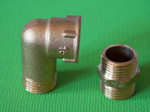 Brass adapter elbow with external-internal thread and brass nipple, used to connect pipes with threaded fittings of the same diameter.