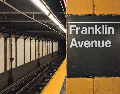 Franklin Avenue sign on platform inside train station (brooklyn new york underground subway stop) crown heights (2,3,4,5 trains and s shuttle) metro rail tracks