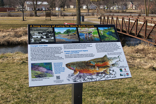 Close-up of a sign describing restoration and conservation efforts beside Black Earth Creek in Cross Plains, WI.