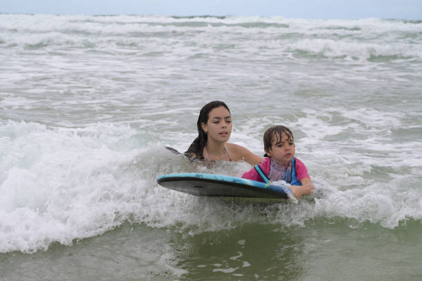 istock brothers playing with surfboard in the waves on the shore 2069024324