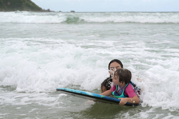 istock brothers playing with surfboard in the waves on the shore 2069026412