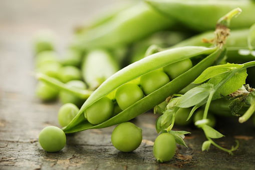 Green pea pods on wooden table