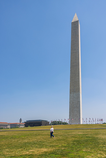Mature Caucasian woman strolling on the grass at the National Mall, with the towering Washington Monument in Washington, D.C.