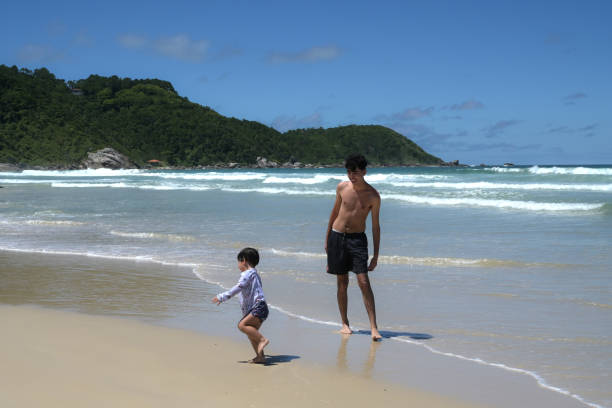istock brothers playing on the seashore 2069042643