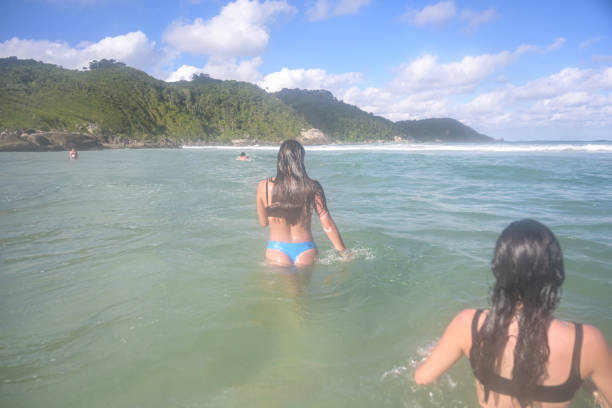 Blue water, white sand and mountains on background, a man tudinho a bike far away
