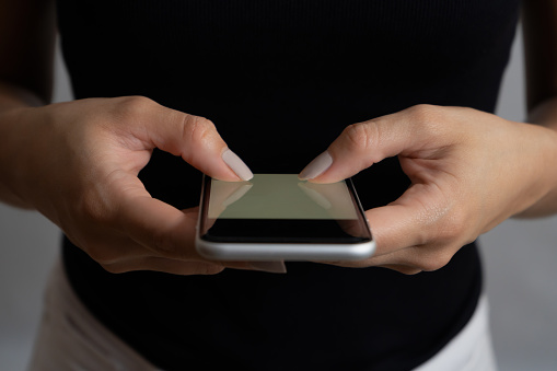 Cropped shot of woman using cell phone, blank mobile screen