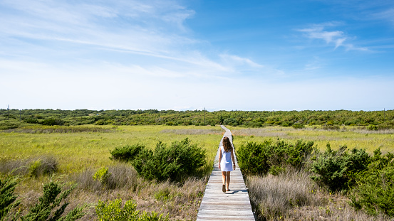 Rear view of a girl walking away on a boardwalk in a remote location