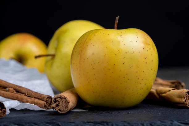 Ripe organic red apple and cinnamon stick on wooden table background.