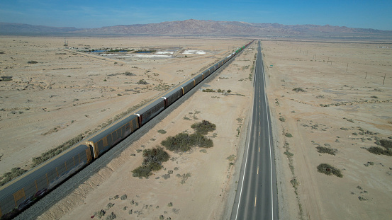 Aerial view of highway and freight train running parallel on the Mojave desert