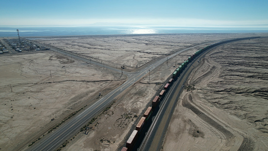 Aerial view of highway and freight train running parallel on the Mojave desert