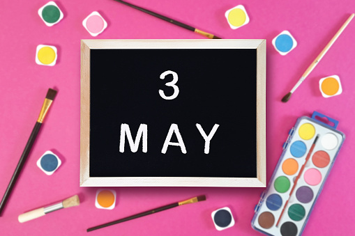 Calendar date 3rd of May on chalkboard on pink blurred school stationery background. Event schedule date. School, study, education concept. Month of spring.