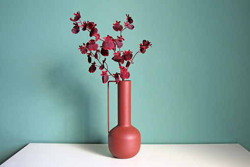 Blooming branch in a modern ceramic vase on a white table. Oriental style design. Space for your text.