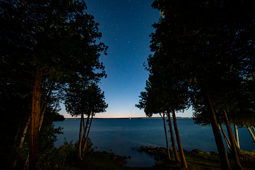 View of night Lake Manitou from the cabin. Dark sky line with stars, landscape with trees and water. Canadian wilderness. Perfect spot for a holiday. Cottage located on the largest fresh water island.