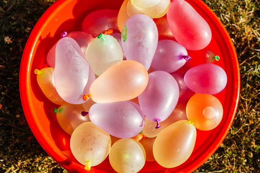 Plastic container full with balloons filled with water, ready for water bomb children  fun in the yard.
