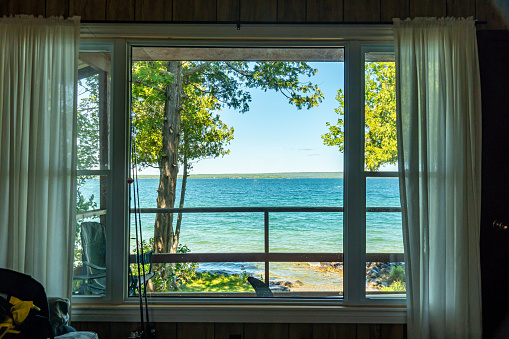 View of the beautiful Lake Manitou into the cabin window. Amazing sky line landscape with trees and water. Canadian wilderness. Spot for a holidays. Cottage located on the largest fresh water island.