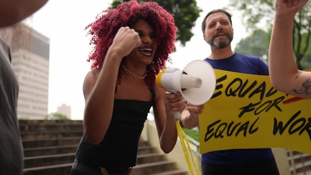 Transgender person leading protest and talking on megaphone outdoors