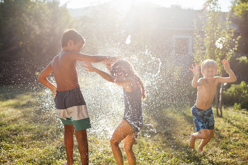 Group of children having fun in the yard with , fighting with water bombs with balloons filled with water, and refreshing on a hot summer day