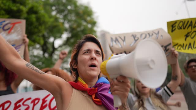 Young woman talking in a megaphone during a protest in the street