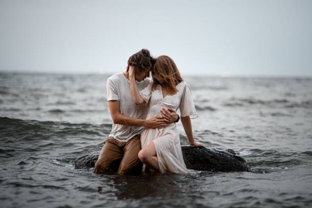 istock Young couple sits in the water on a rock and hugging 2069217848