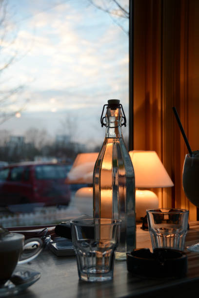 A carafe of water on a blurry background with colored bottles