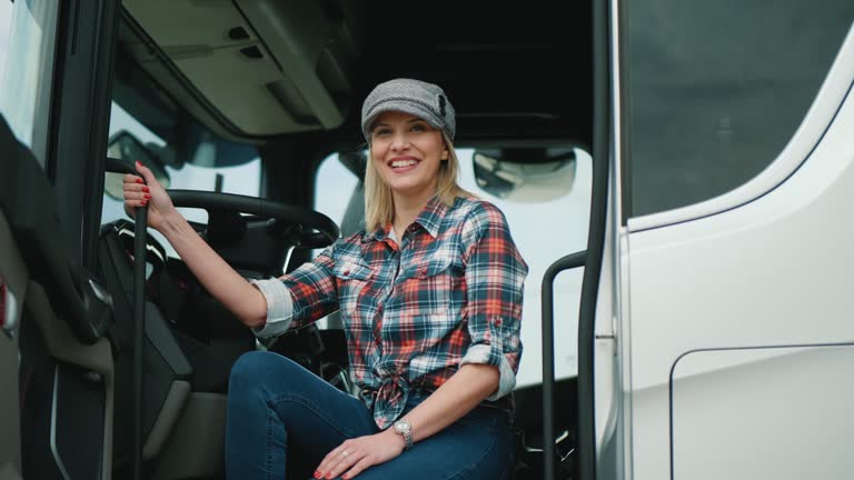 Portrait of smiling woman truck driver sitting in the cab and looking at the camera