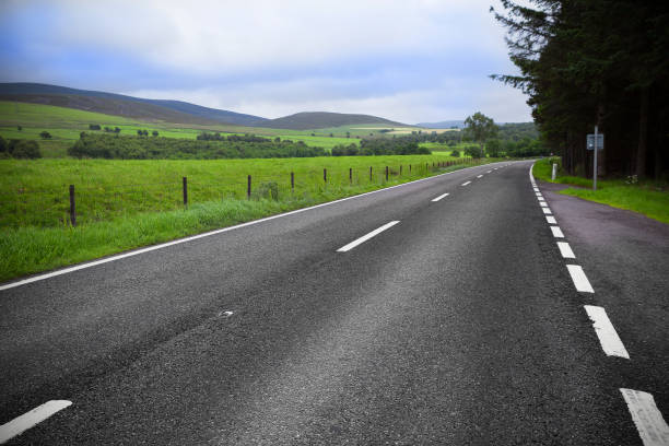 istock Asphalt road through the green field and clouds on blue sky 2069285776