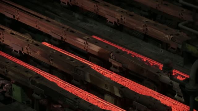 Glowing molten metal being cast in industrial setting, dark ambience