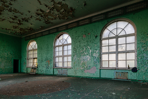 Large hall of abandoned building with peeled paint.