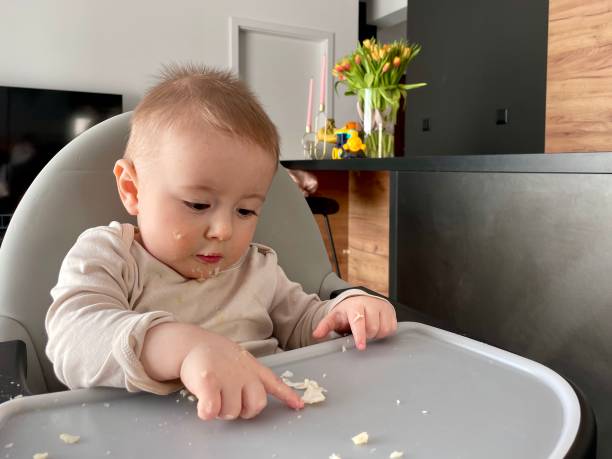istock A little baby boy sits at the feeding table and eats by himself 2069468207