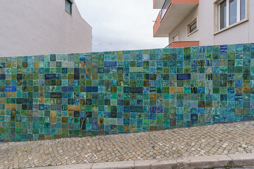 Wall besides street covered with green, blue and turquoise tiles, Lisbon, Portugal