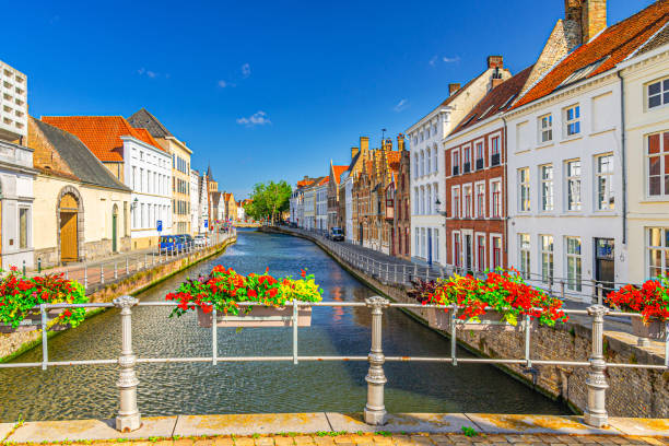 Flowers pots on fence of Sint-Annarei Bridge across Sint Annarei water canal of Reie river with buildings along promenade, Bruges city historic centre, Brugge old town quarter, West Flanders, Belgium macetas de flores en la valla del puente sint-annarei a través del canal de agua sint annarei del río reie con edificios a lo largo del paseo marítimo, centro histórico de la ciudad de brujas, casco antiguo de brujas, flandes occidental, bélgica