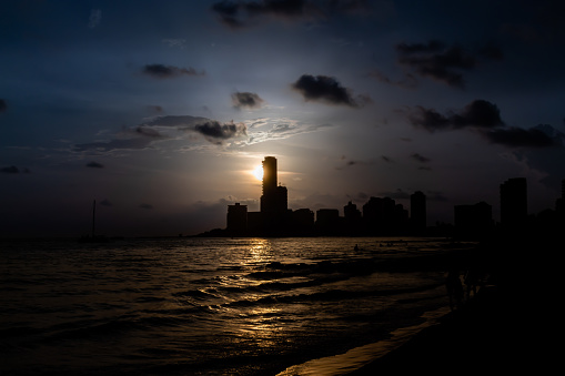 buildings seen from the beach as the sun sets, leaving a colorful sky and giving way to the quiet night.