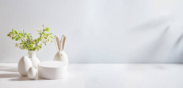 istock Empty round white podium for product presentation. Spring flowers in a vase and easter eggs on a light background 2069623339