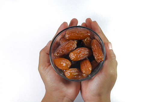 hand holding bowl of date fruits isolated on white, ramadan concept