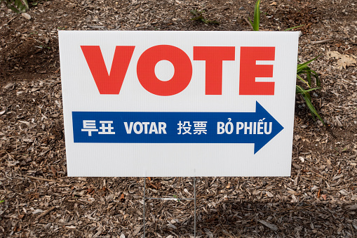 A multilingual voting sign with arrow in red white and blue.