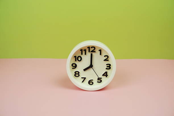istock White alarm clock with space copy on green and pink background 2069737376