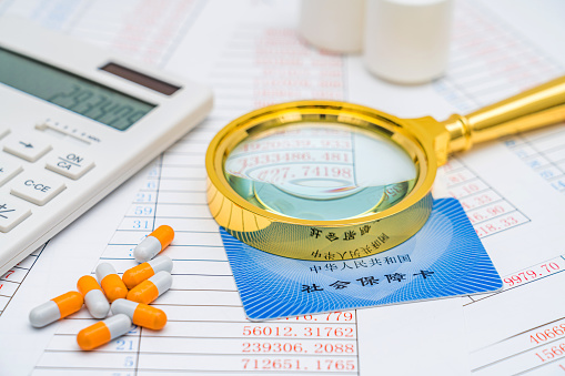Calculator, magnifying glass social security card, and medication - concept of medical insurance
