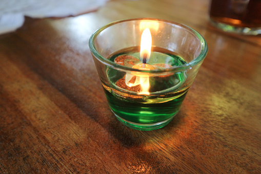 View of a lit oil candle in a glass