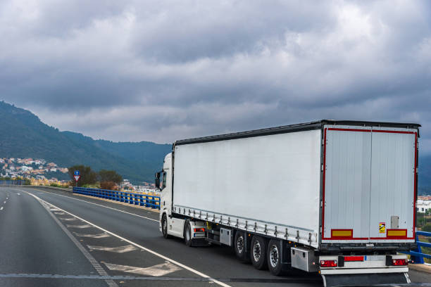 istock Truck with semi-trailer with awning for general cargo joining a highway, rear view. 2070095571