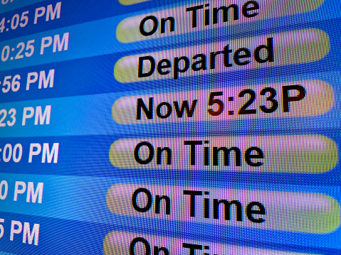 An airline departures display in an airport terminal informs passengers of multiple flight statuses at a busy international airport.