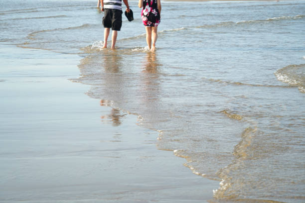 close up on a couple walking in the beach with reflection