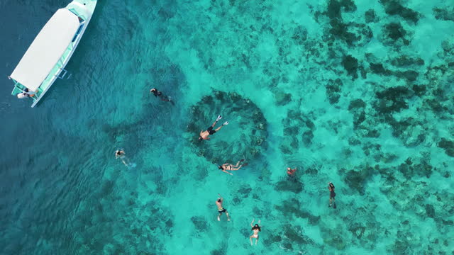 Aerial view of people snorkeling near underwater statues on Gili Meno