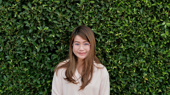 Young woman with clear glasses With a wall covered with green grass
