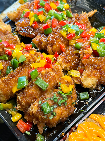Stock photo showing fast-food takeaway tray with rows of golden brown crispy, Southern fried chicken recipe, deep-fried in hot oil with seasoned spicy batter coating, herbs, flour and breadcrumbs.