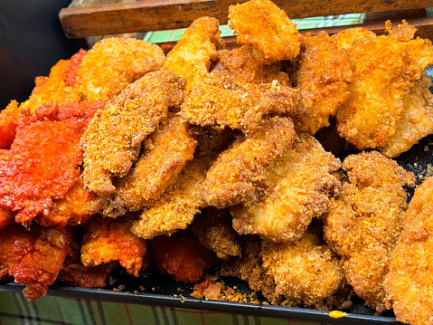 Stock photo showing fast-food takeaway tray piled high with golden brown crispy, Southern fried chicken recipe, deep-fried in hot oil with seasoned spicy batter coating, herbs, flour and breadcrumbs.
