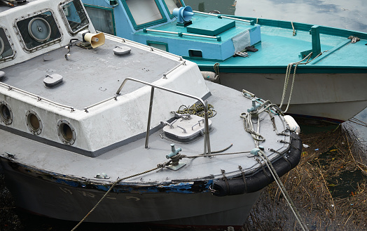 Sight of the bow of two workboats moored with ropes in the harbor