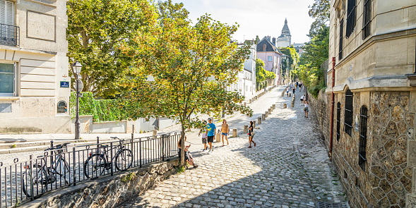 Paris, France - September 10, 2023 : Typical cobblestone street of Montmartre with tourists visiting