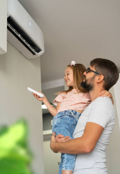 Happy girl holds remote control from air conditioner sitting in fathers hands Happy little girl holds remote control from air conditioner sitting in fathers hands in light interior of apartment. Family turn on air conditioner air conditioner family stock pictures, royalty-free photos & images