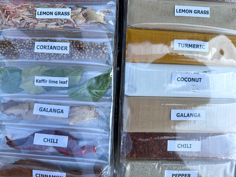 Stock photo showing a close-up, elevated view of prepackaged cellophane bags of dried and powdered herbs and spices being sold by from a street market display.